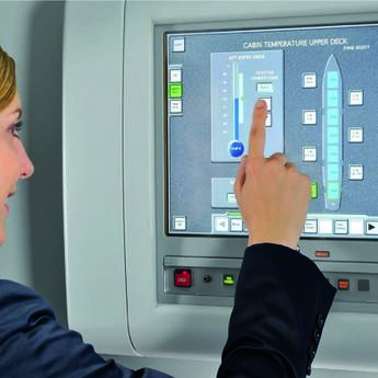 A flight attendant in uniform operating the Flight Attendant Panel (FAP) on the aircraft.