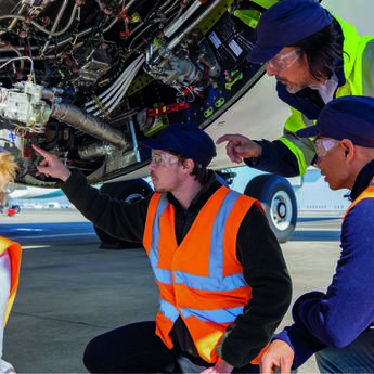 Maintenance training in action with mechanics in safety vests and goggles detecting and inspecting aircraft components