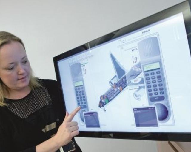 Cabin Crew Training Suites_digital An instructor in a cabin training session presenting the handset trainer