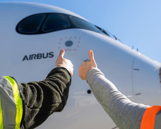 Airbus maintenance people on ground with thumbs up Airbus maintenance people on ground with thumbs up