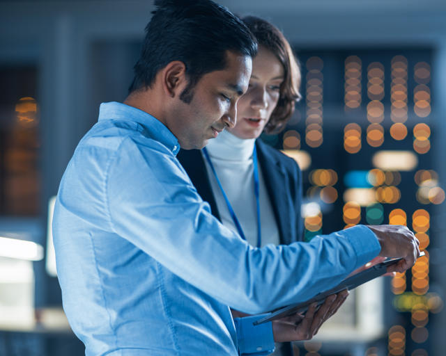 Two people working, looking at a tablet. Two people working, looking at a tablet.
