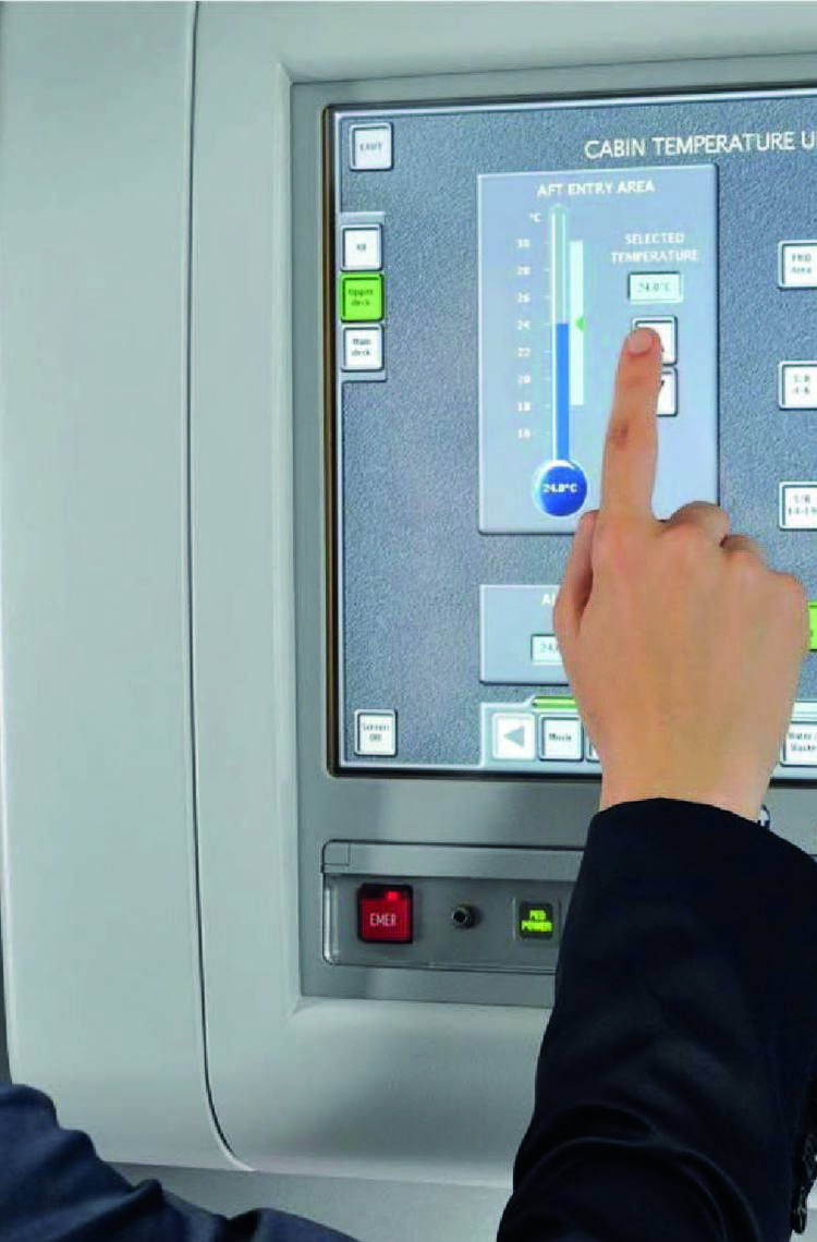A flight attendant in uniform operating the Flight Attendant Panel (FAP) on the aircraft.