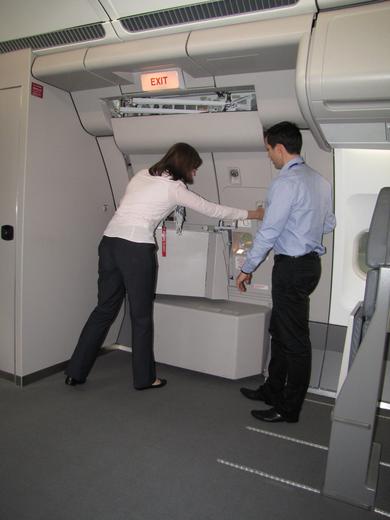 An instructor demonstrating and guiding a cabin crew trainee in closing the door of an aircraft during the training session.